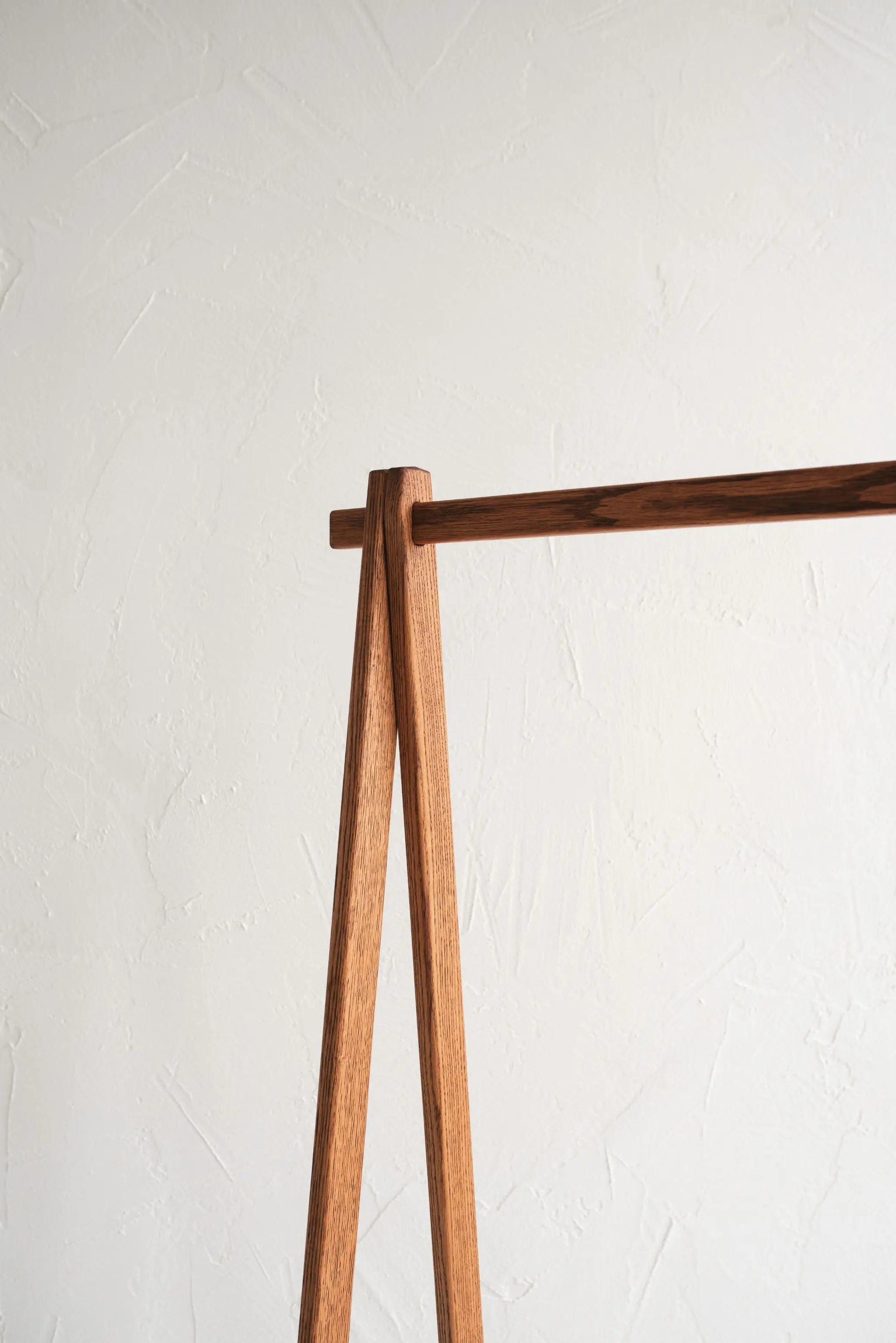 Wooden coat rack against a white wall