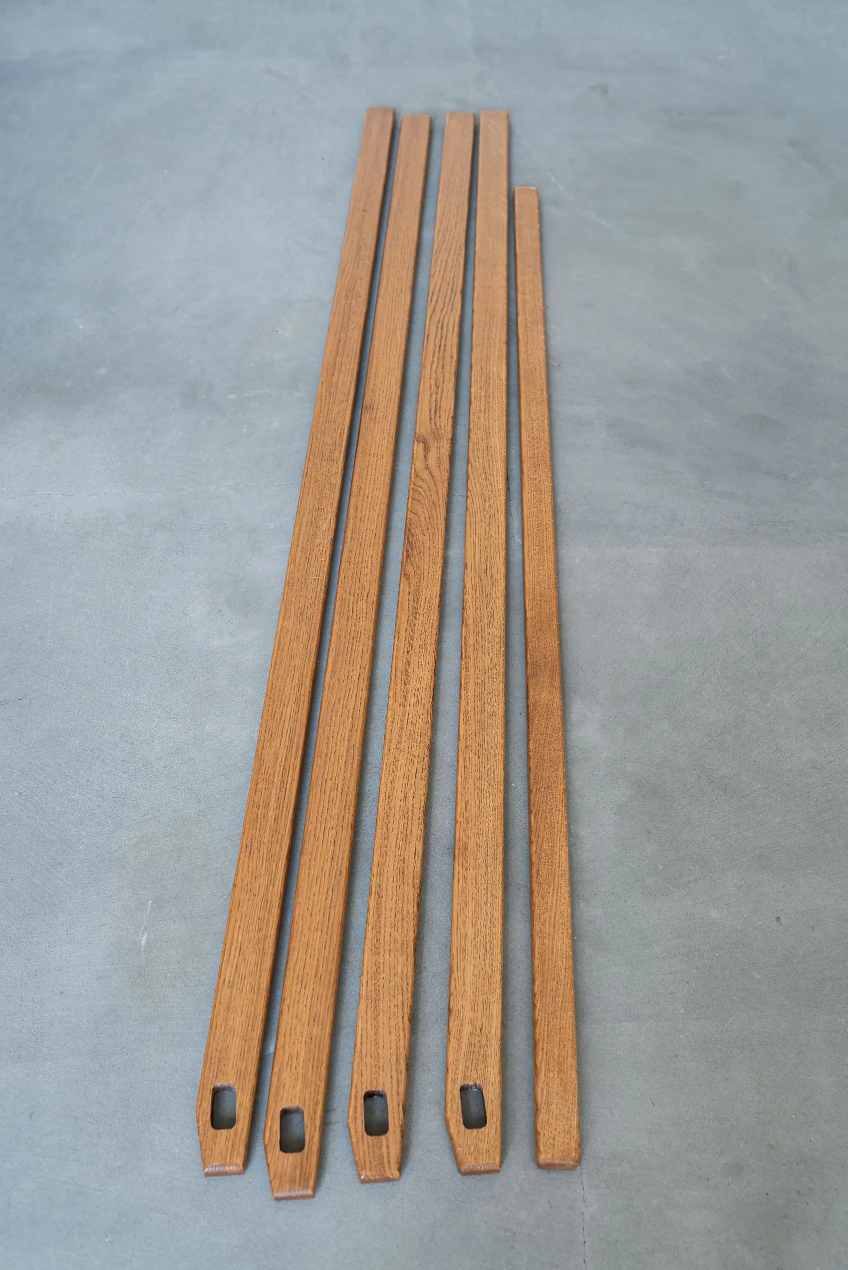 Four wooden strips with metal brackets on a gray surface