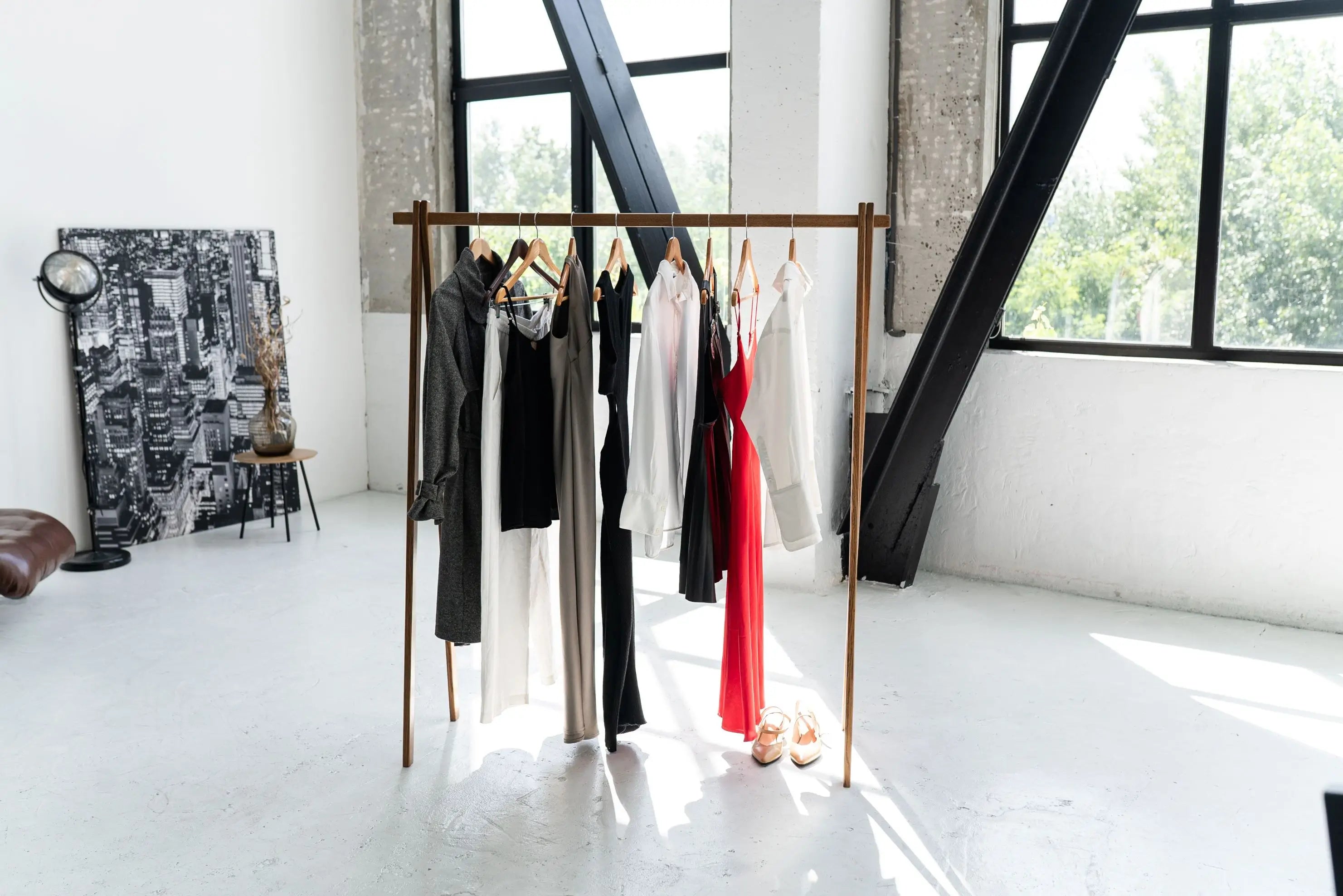 Clothing rack with clothes in a room with large windows and a white floor.