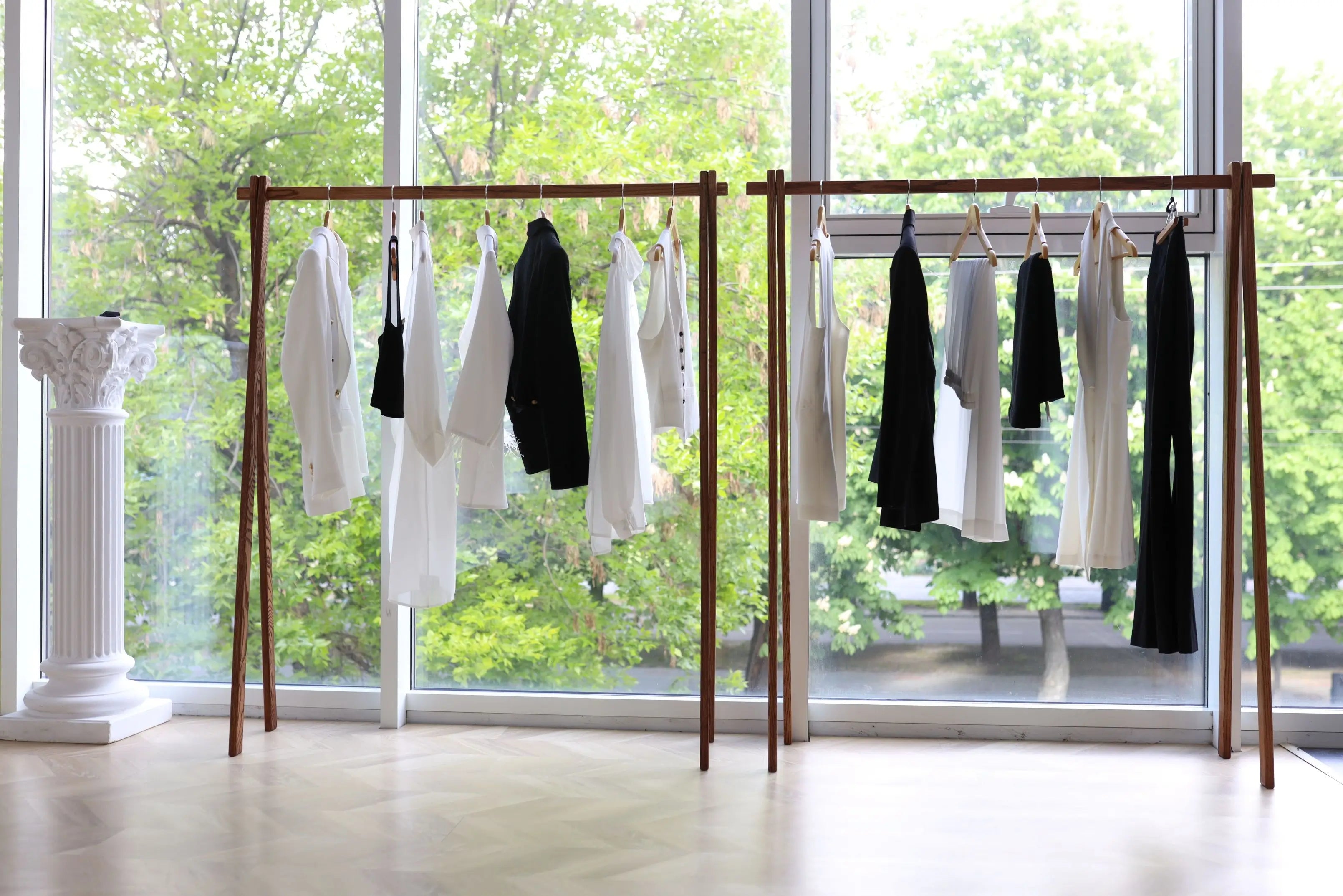 Clothing rack with clothes in a room with large windows showing greenery outside
