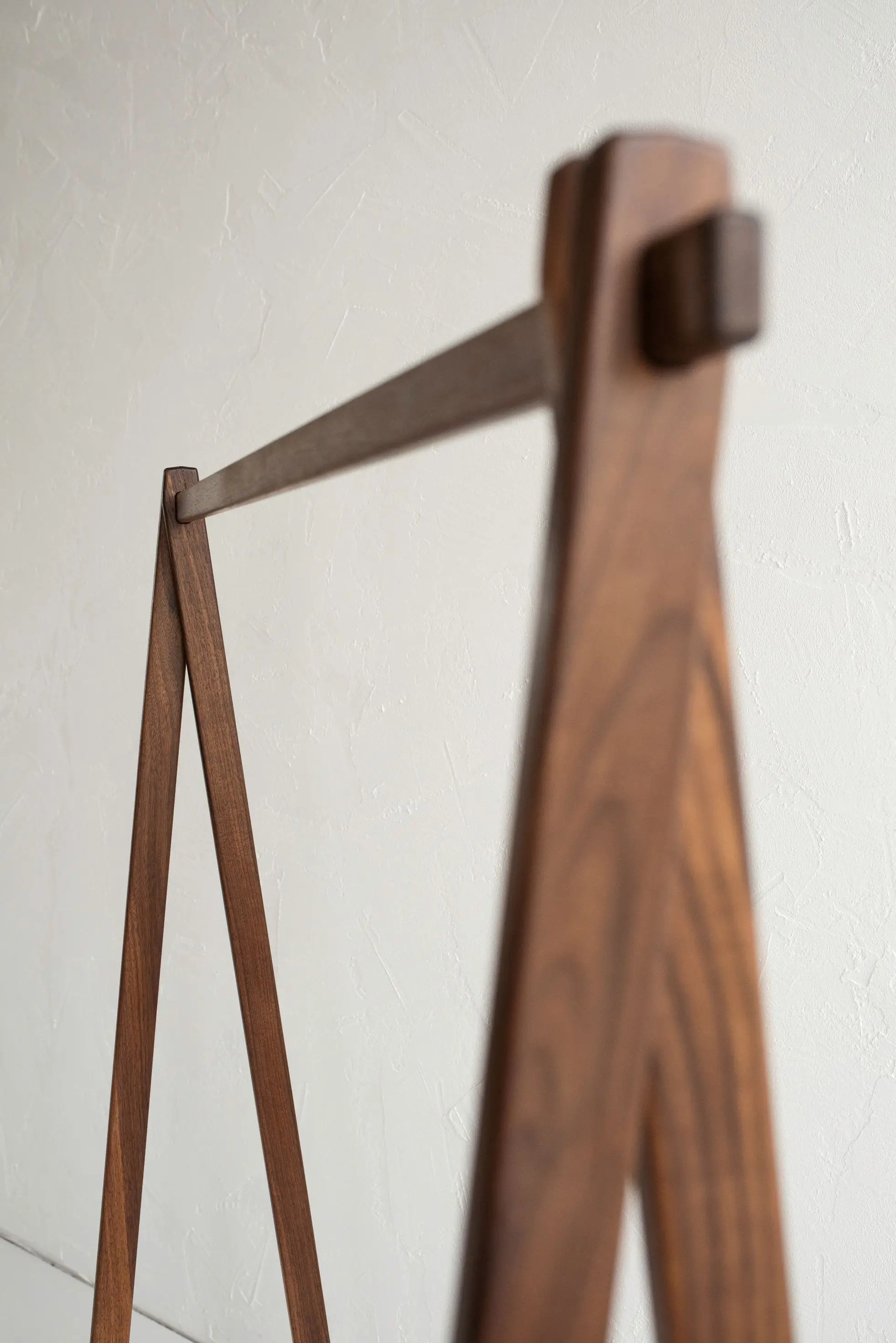 Wooden coat rack against a white wall