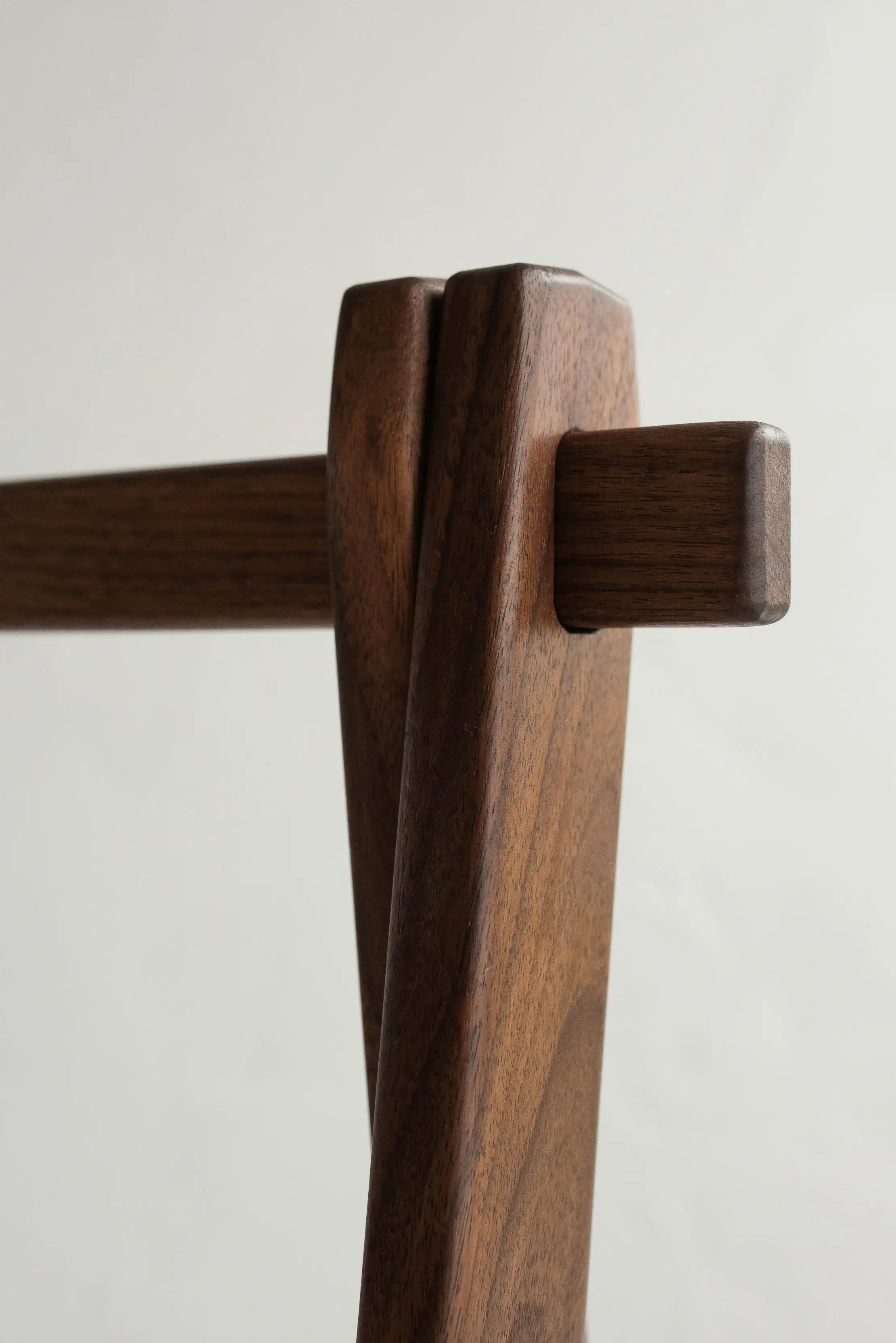 Close-up of a wooden chair armrest on a plain background