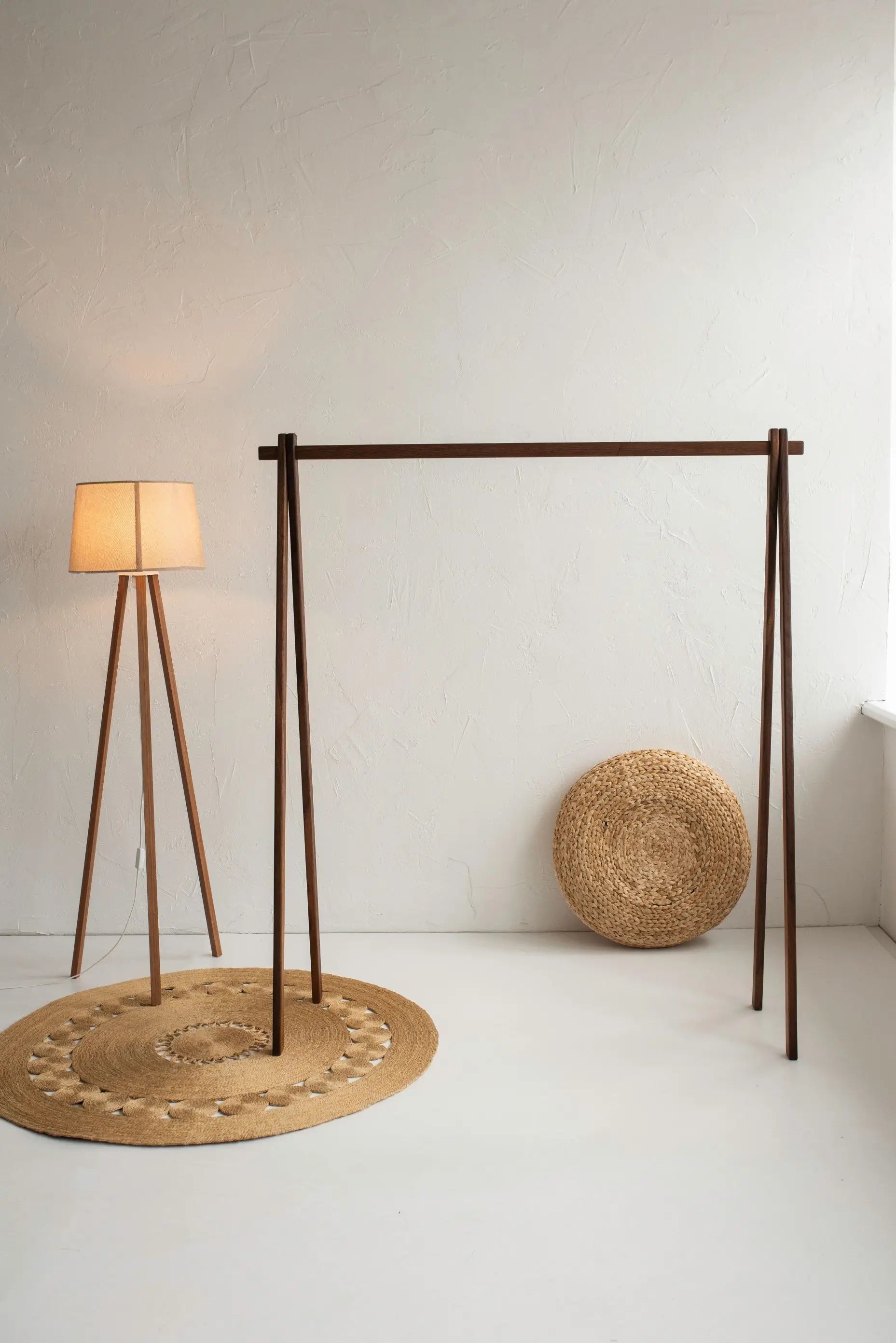 Modern lamp with a woven base and round basket on a white floor against a white wall.