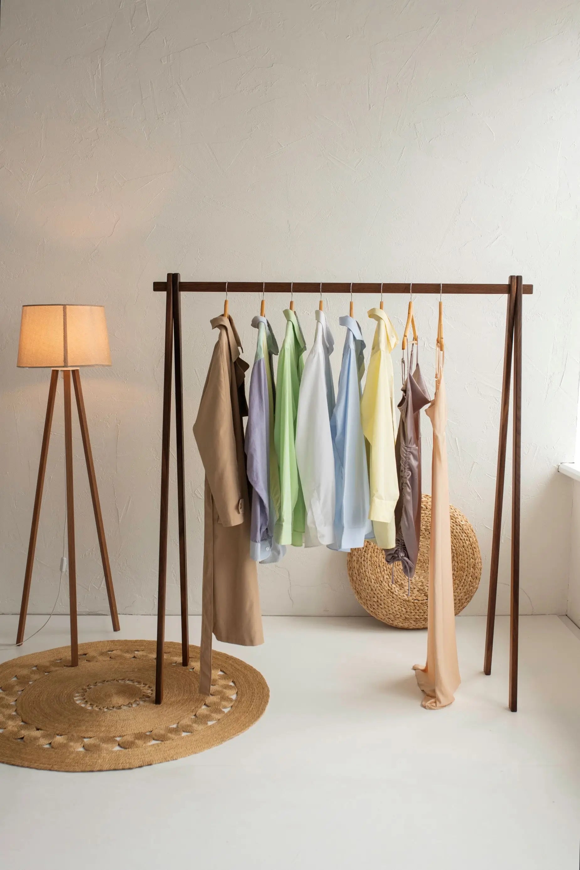 Clothing rack with hanging clothes next to a floor lamp in a room.