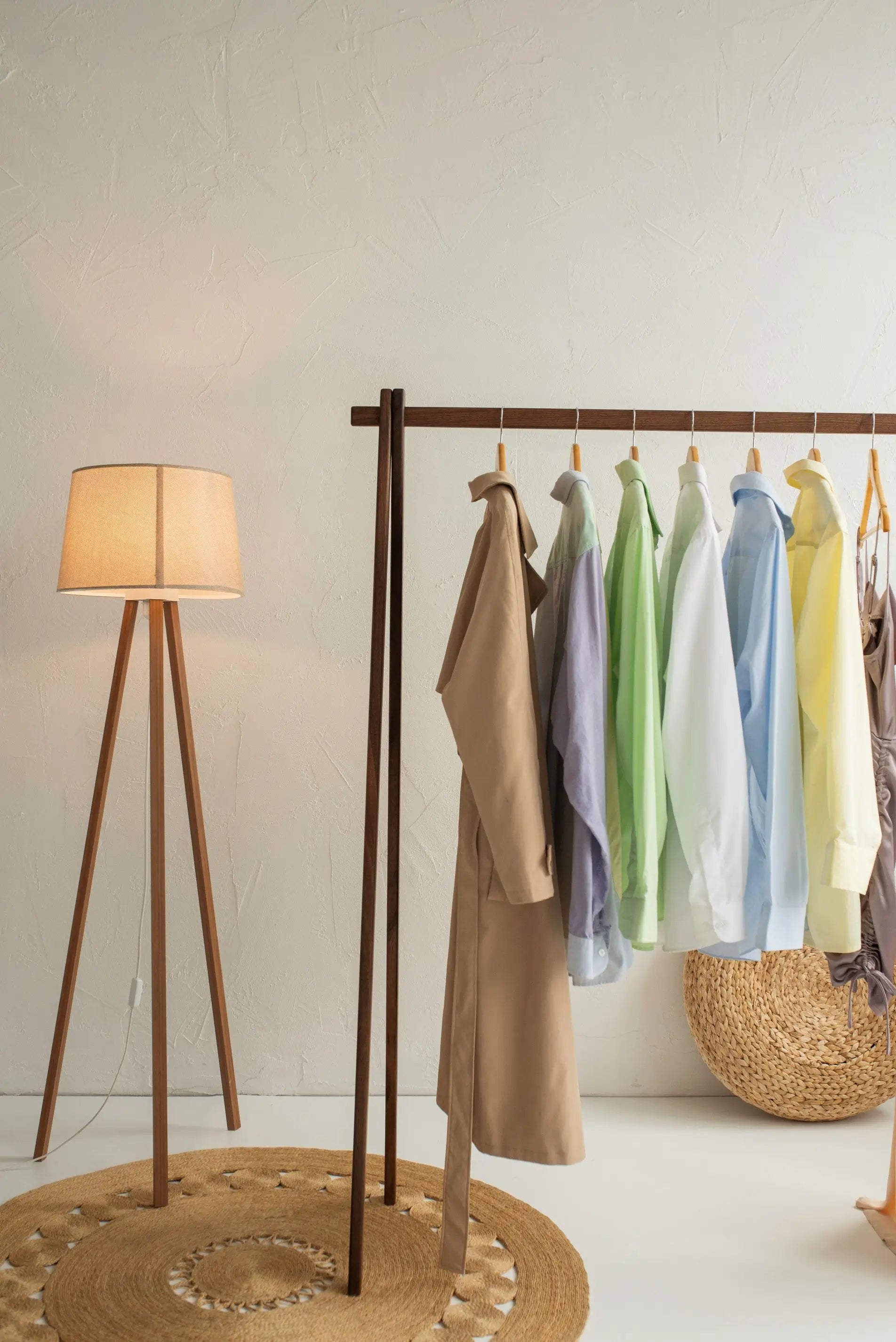 Clothing rack with dresses in various colors next to a floor lamp in a room.