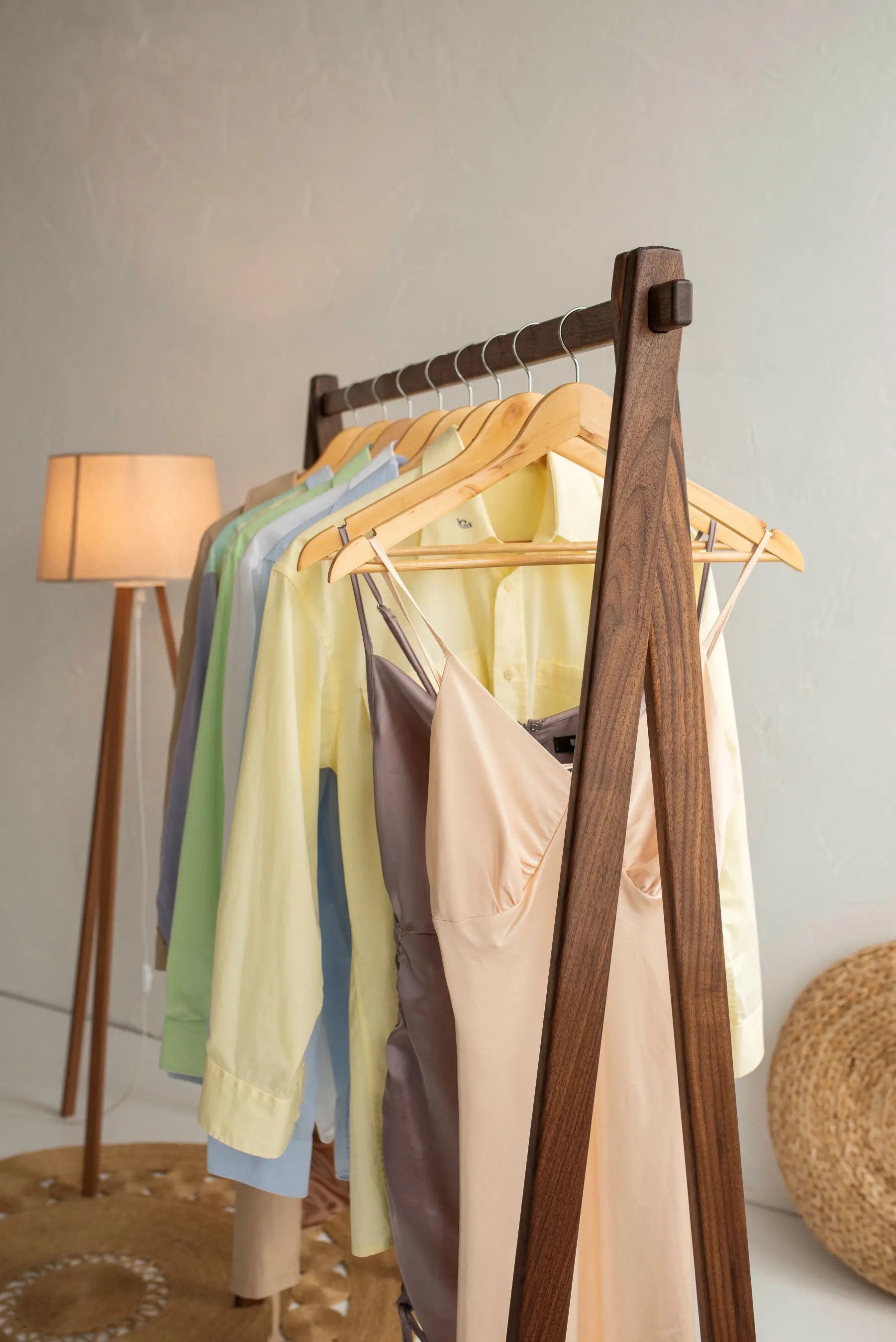 Clothing rack with various garments hanging on it against a neutral background