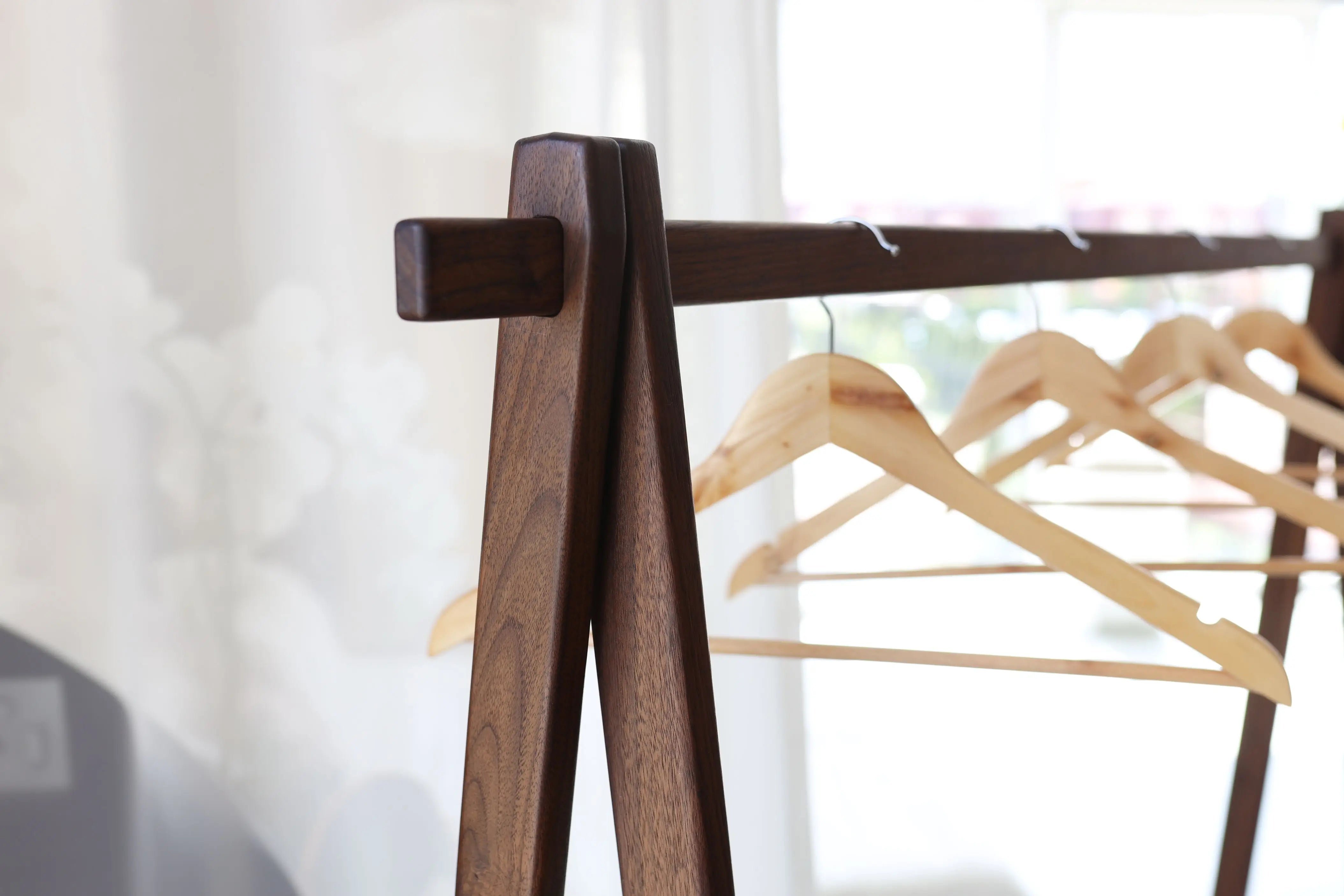 Wooden hanger stand with wooden hangers against a blurred background