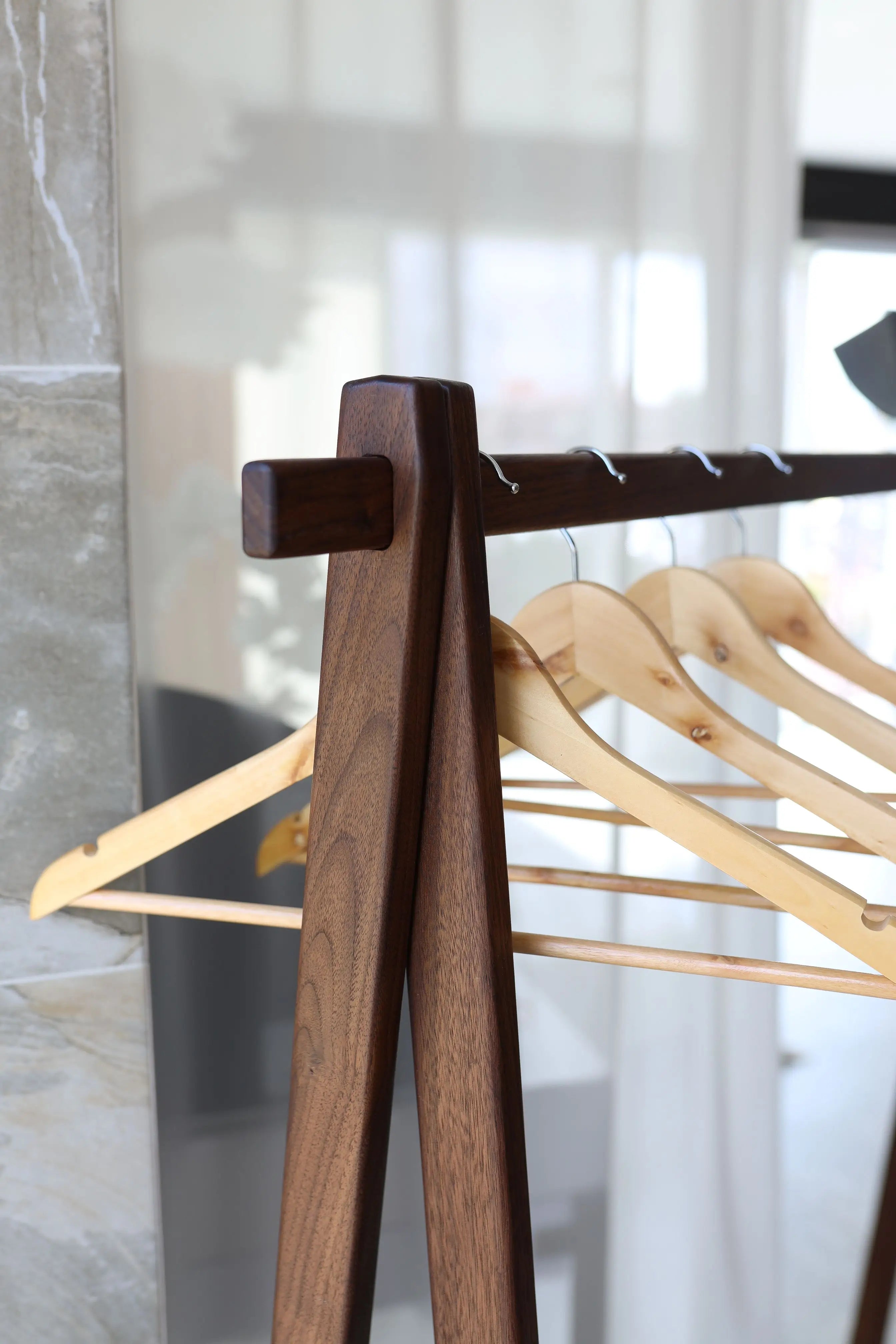 Wooden hanger stand with wooden hangers against a neutral background