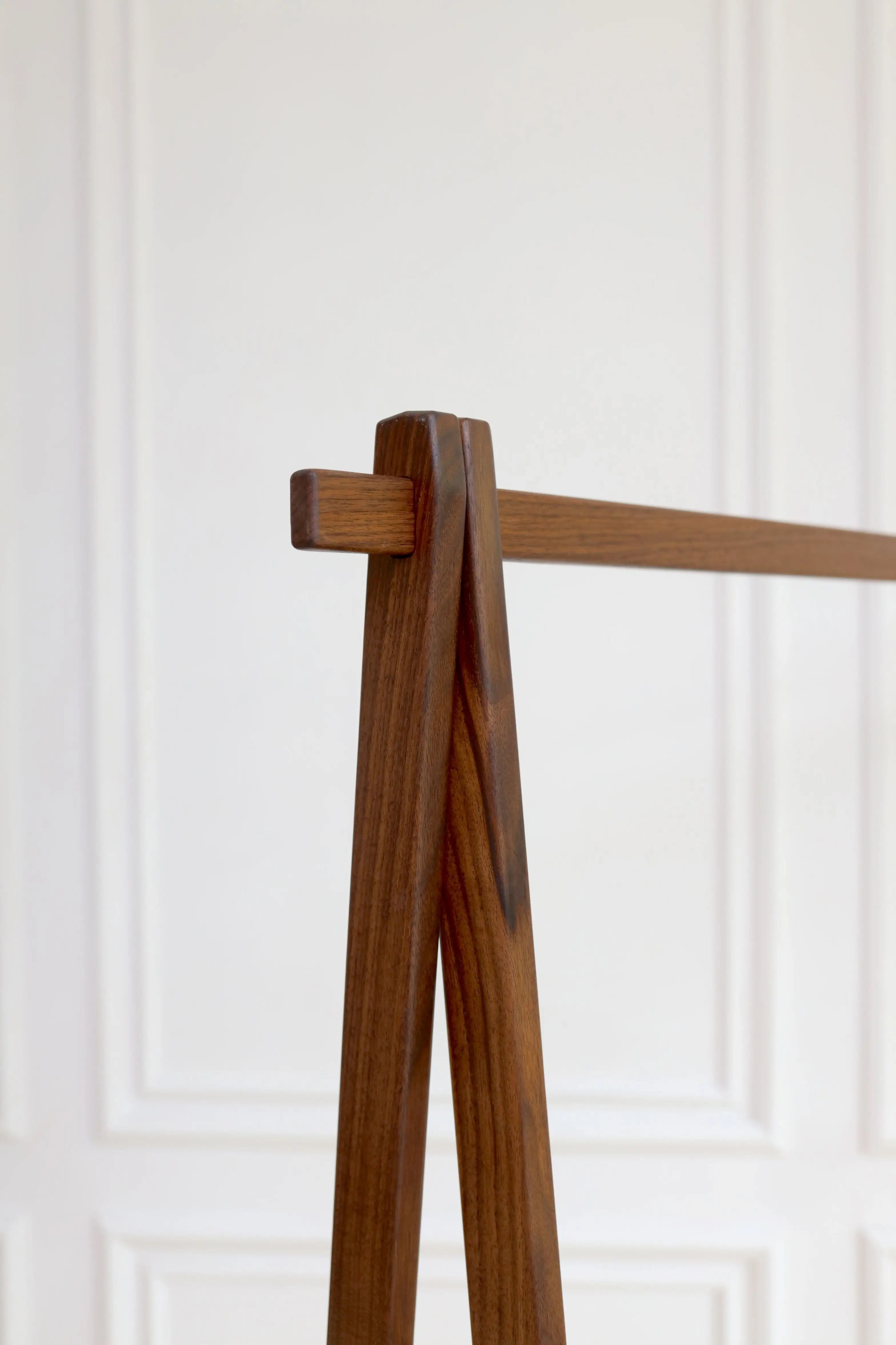 Wooden coat rack against a white paneled wall